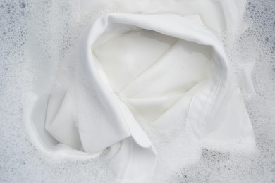 Photo of White clothing in suds, top view. Hand washing laundry