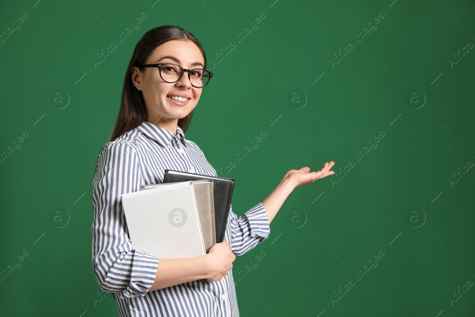 Photo of Portrait of young teacher with notebooks on green background. Space for text