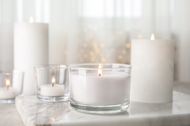 Photo of Burning aromatic candles in holders on table