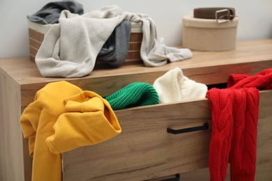 Photo of Cluttered chest of drawers indoors, closeup. Clothes in mess