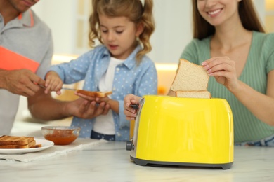 Happy family having breakfast with toasted bread at table in kitchen, closeup