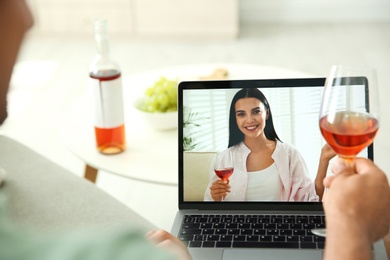 Photo of Friends drinking wine while communicating through online video conference at home. Social distancing during coronavirus pandemic