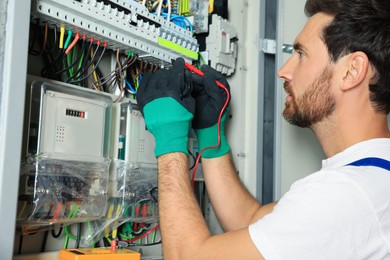 Photo of Electrician checking electric current with multimeter indoors, closeup