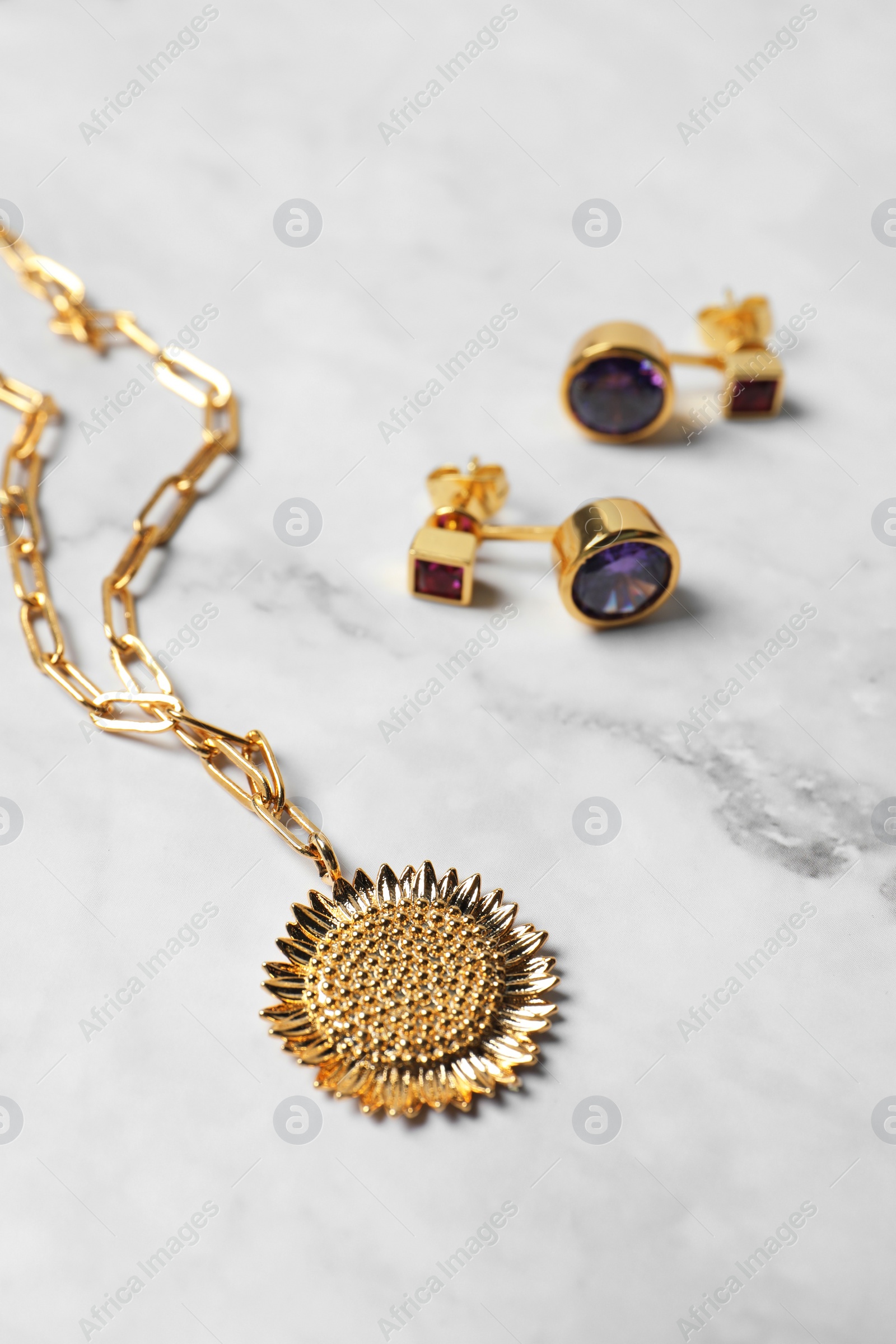 Photo of Elegant necklace and earrings on white marble table, closeup