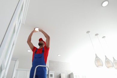 Electrician repairing ceiling lamp indoors, low angle view. Space for text