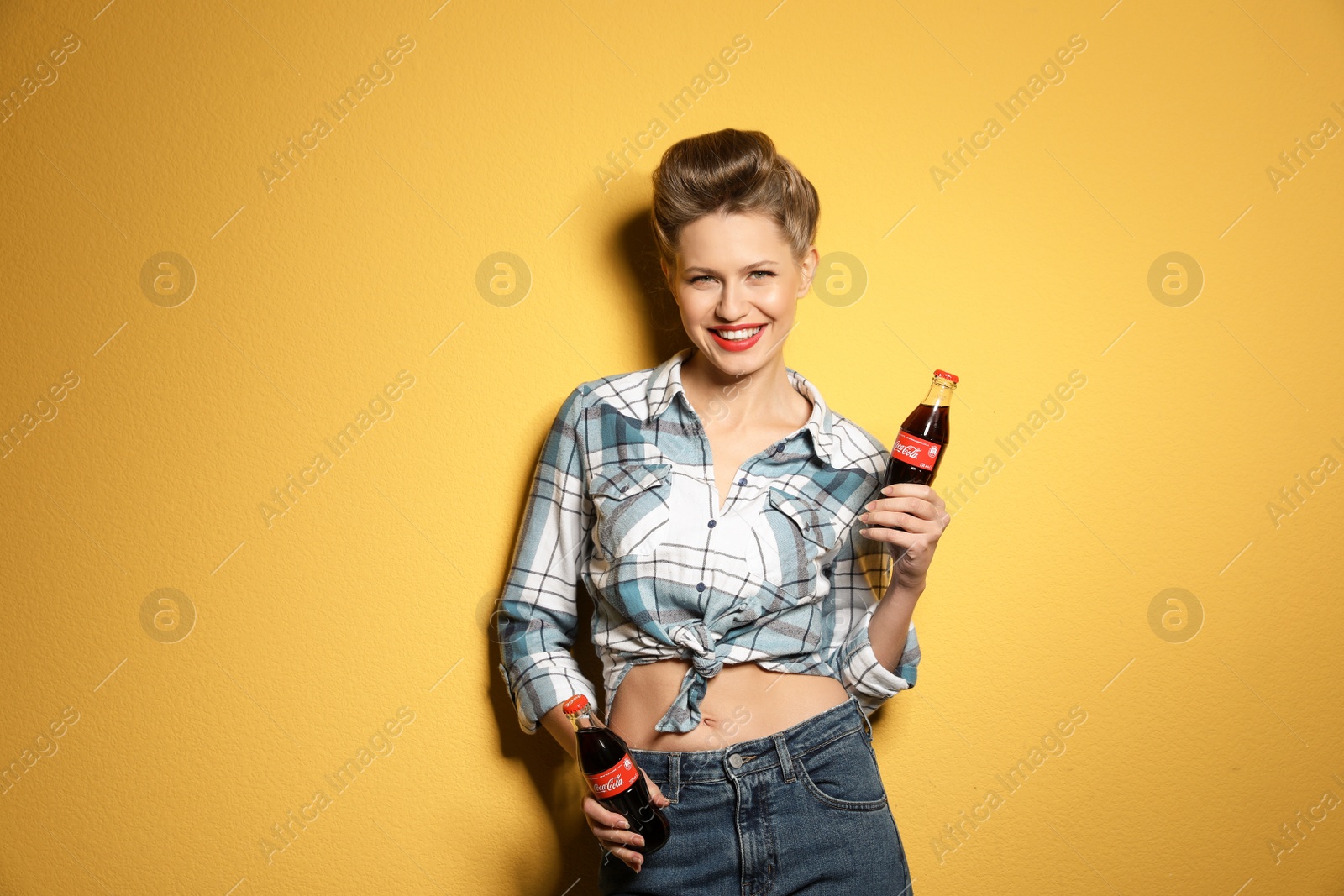 Photo of MYKOLAIV, UKRAINE - NOVEMBER 28, 2018: Young woman with bottles of Coca-Cola on color background