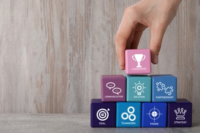 Closeup view of man stacking colorful cubes with different images at wooden table, space for text. Management concept