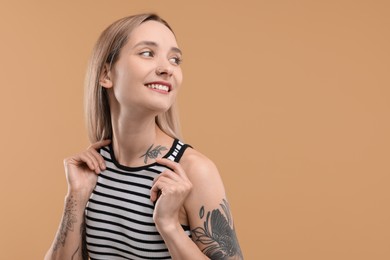 Portrait of beautiful tattooed woman on beige background, space for text