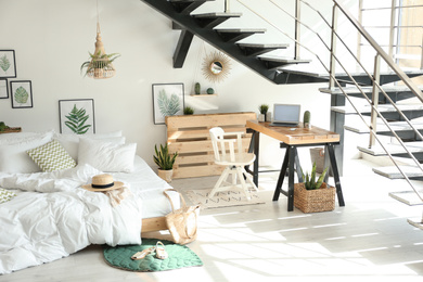 Elegant interior of bedroom with workplace under stairs