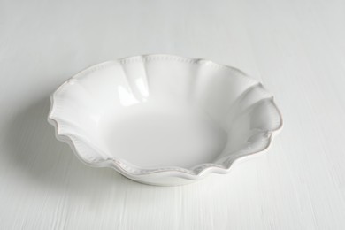 Empty ceramic bowl on white wooden table, closeup