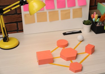 Photo of Business process scheme with geometric figures and stationery on wooden table