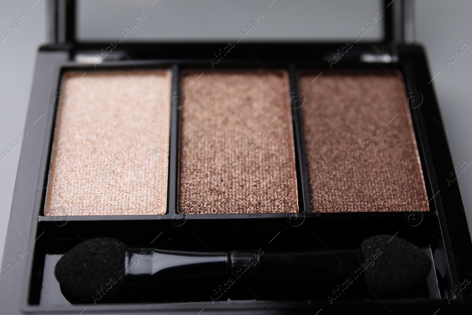 Photo of Beautiful eyeshadow palette and applicator as background, closeup. Professional cosmetic product