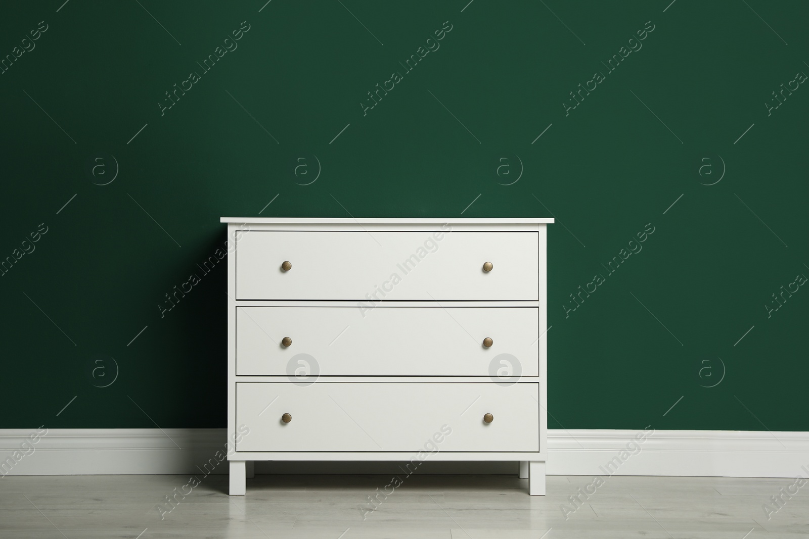 Photo of Modern white chest of drawers near green wall indoors