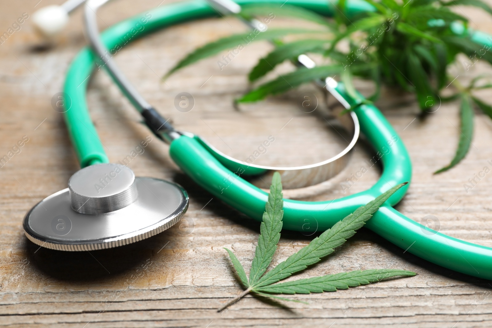 Photo of Hemp leaves and stethoscope on wooden table, closeup