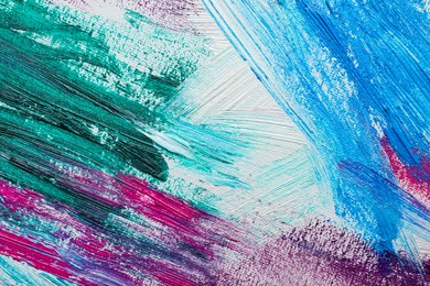 Photo of Strokes of colorful acrylic paints on white canvas, closeup