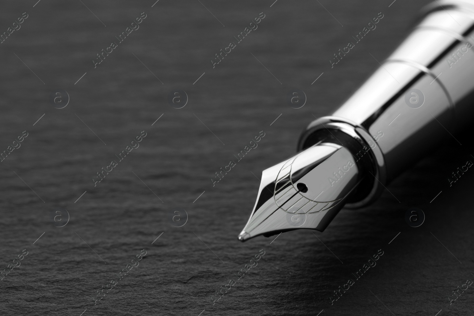 Photo of Stylish fountain pen on dark textured table, closeup. Space for text