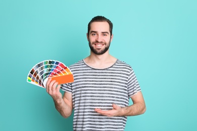 Young man with palette on color background