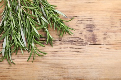 Sprigs of fresh rosemary on wooden table, top view. Space for text