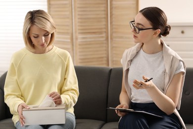 Photo of Professional psychotherapist working with on sofa patient in office