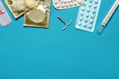 Photo of Contraceptive pills, condoms, intrauterine device and thermometer on light blue background, flat lay with space for text. Different birth control methods