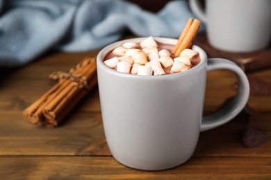 Photo of Delicious hot drink with cinnamon and marshmallows on wooden table, closeup. Space for text