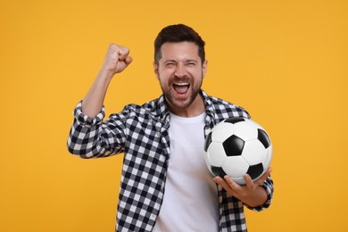 Photo of Emotional sports fan with ball celebrating on yellow background