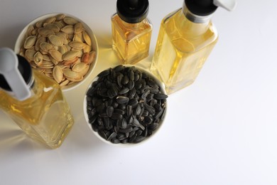 Bottles of different cooking oils and seeds on white background, above view