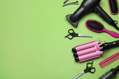 Photo of Flat lay composition of professional hairdresser tools on light green background, space for text