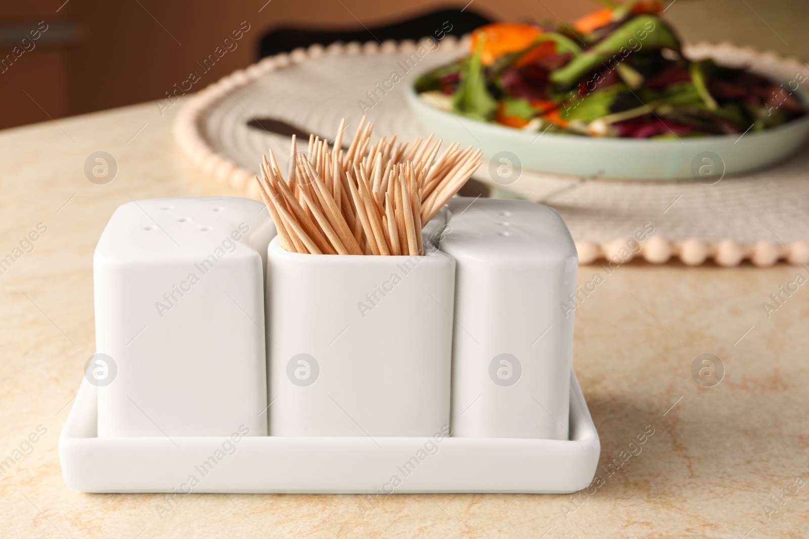 Photo of Holder with salt, pepper and toothpicks on wooden table