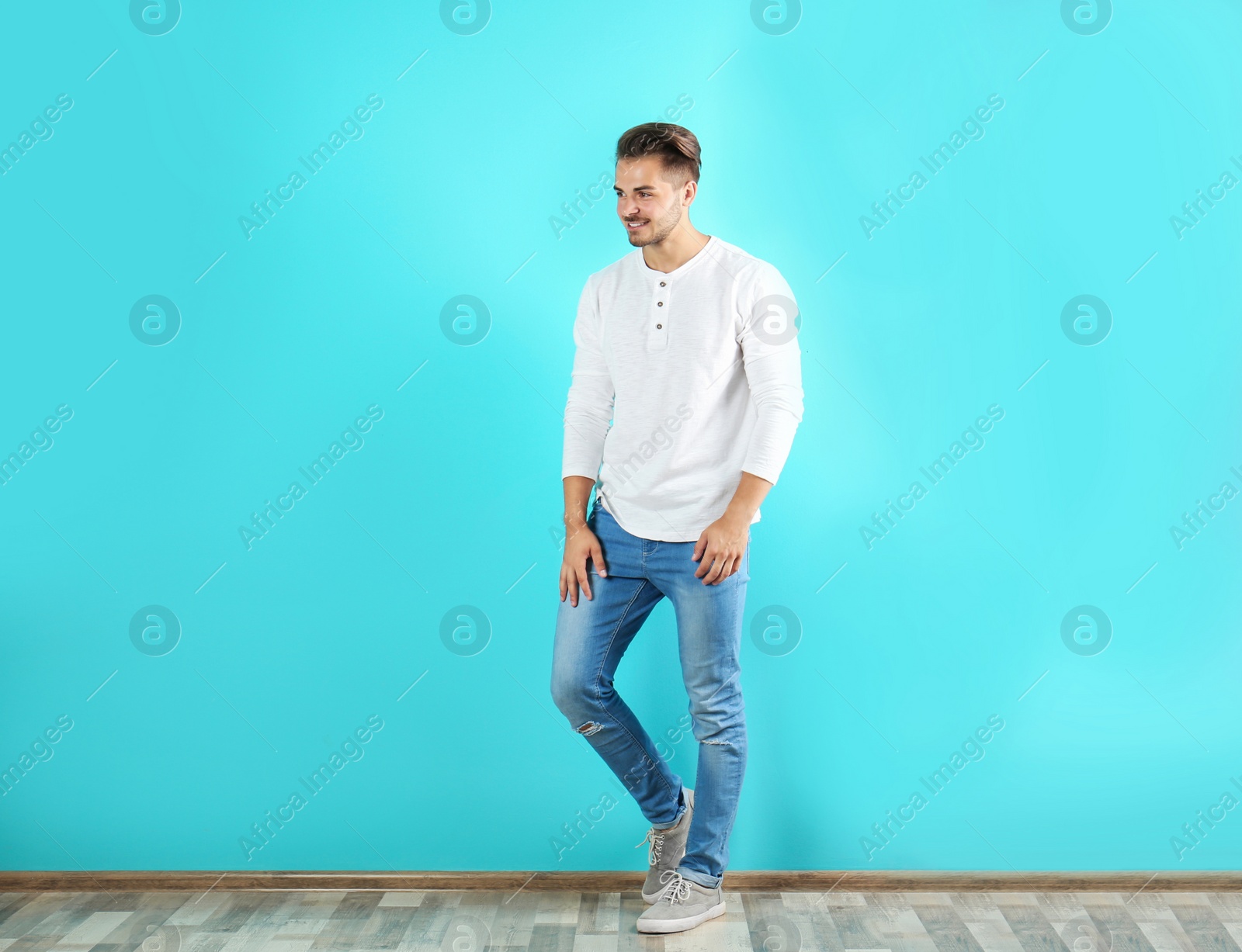 Photo of Young man in stylish jeans near color wall