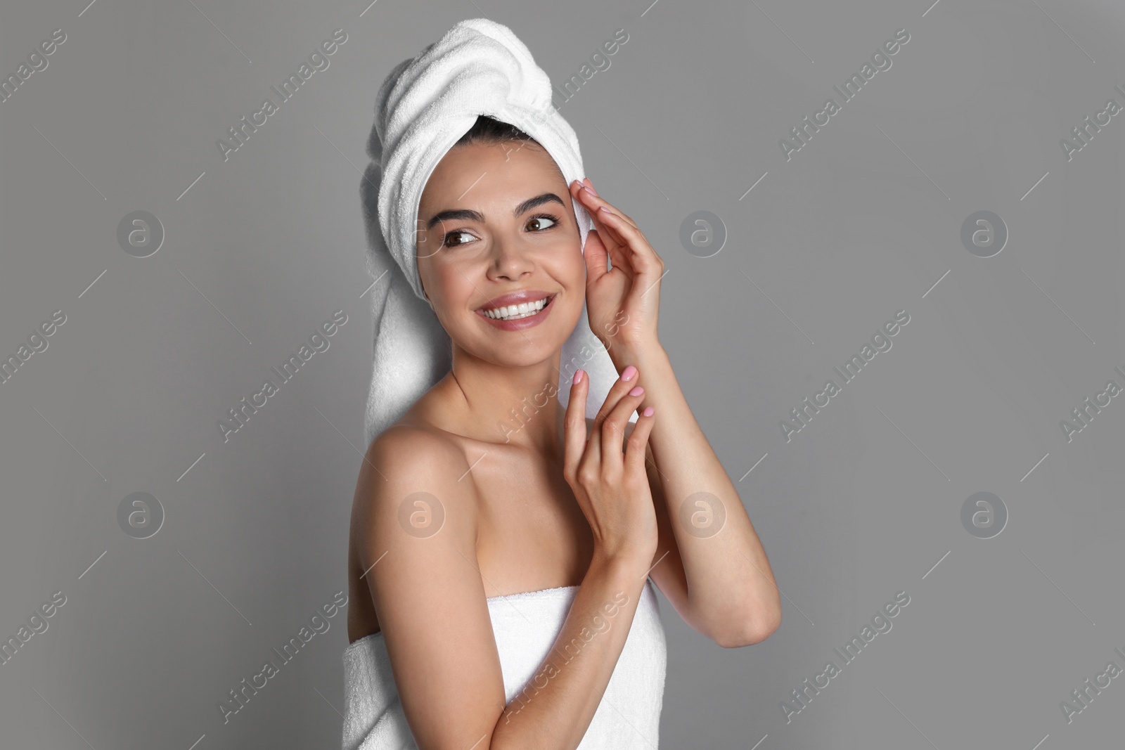 Photo of Beautiful young woman with towels on grey background