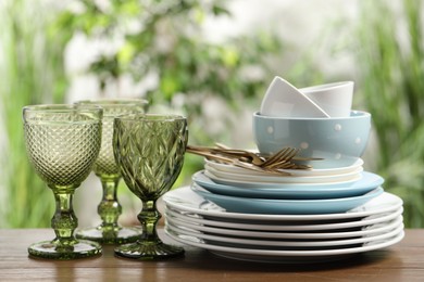 Photo of Beautiful ceramic dishware, glasses and cutlery on wooden table outdoors