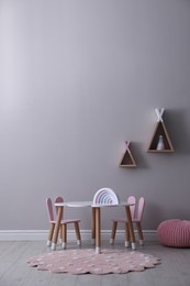Photo of Cute child room interior with furniture, toys and wigwam shaped shelves on grey wall