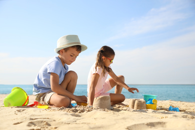 Cute little children playing with plastic toys on sandy beach