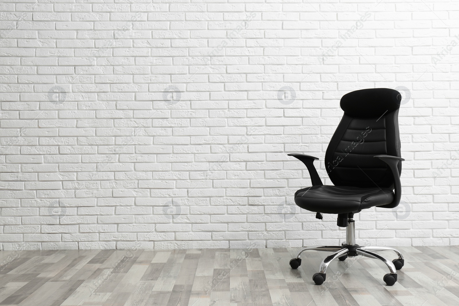 Photo of Comfortable office chair near white brick wall indoors. Space for text