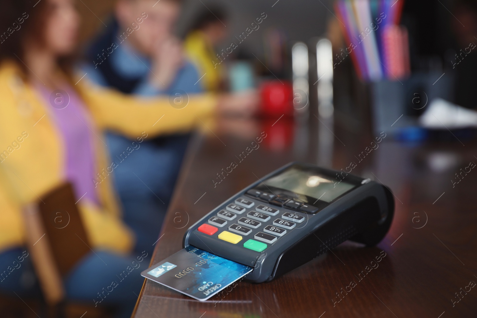 Photo of Credit card machine for non cash payment on wooden counter in cafe. Space for text