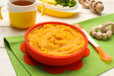 Photo of Plastic dishware with healthy baby food on white table, closeup