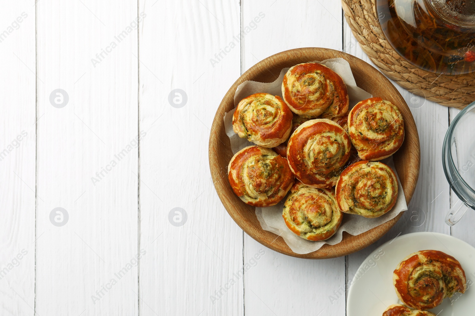 Photo of Fresh delicious puff pastry served with tea on white wooden table, flat lay. Space for text
