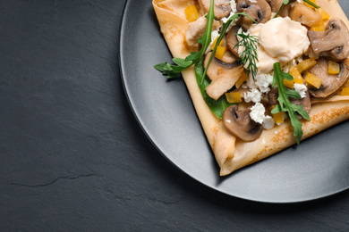 Photo of Delicious breakfast with thin pancakes on black table, top view. Space for text