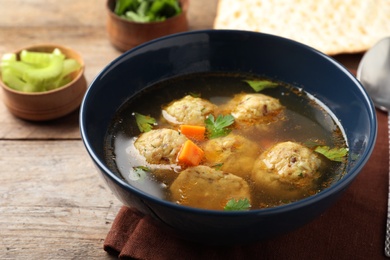 Photo of Bowl of Jewish matzoh balls soup on wooden table
