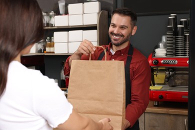 Photo of Worker giving to customer package with fresh pastries in cafe