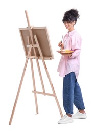 Photo of Young woman painting on easel with canvas against white background