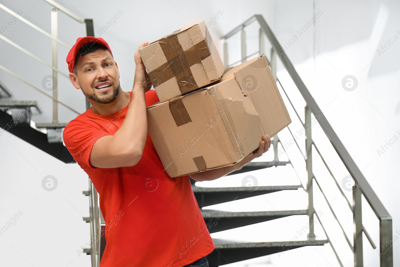 Photo of Emotional courier with damaged cardboard boxes indoors. Poor quality delivery service