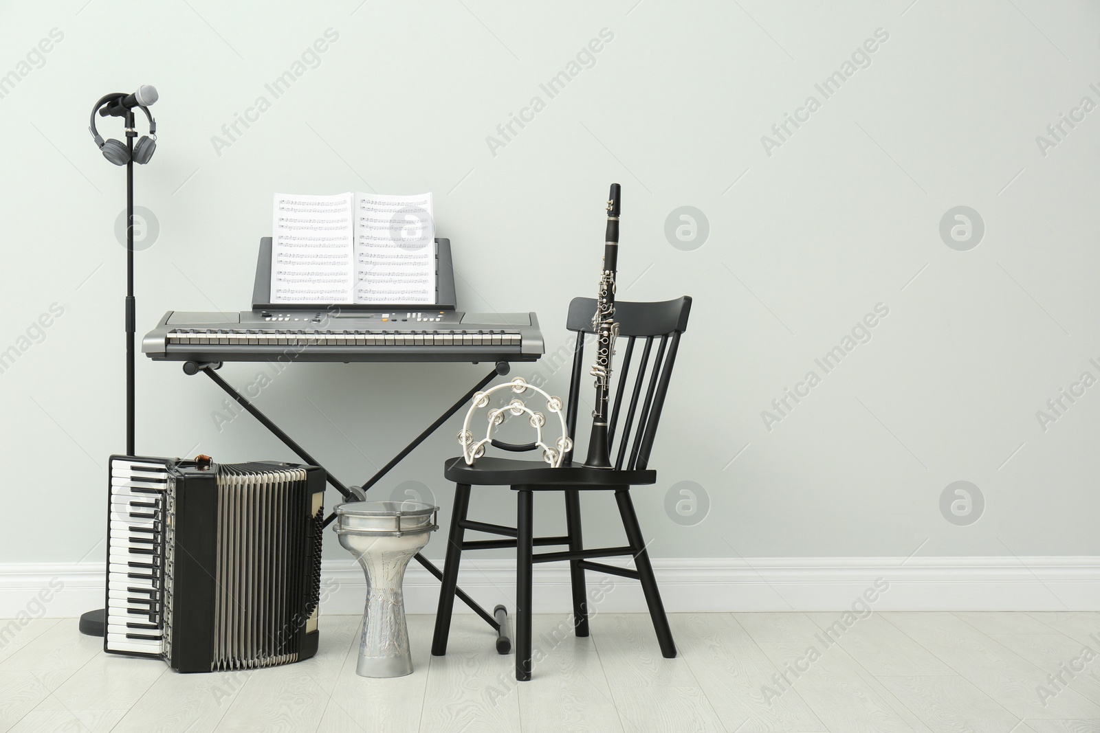 Photo of Set of different musical instruments and microphone near white wall indoors, space for text