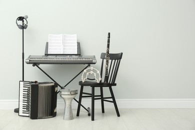 Set of different musical instruments and microphone near white wall indoors, space for text