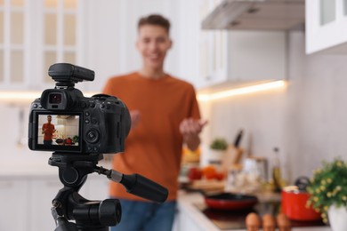 Photo of Food blogger recording video in kitchen, focus on camera