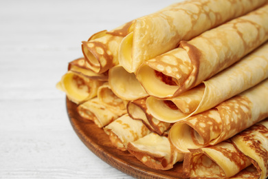 Photo of Fresh thin pancakes on white wooden table, closeup