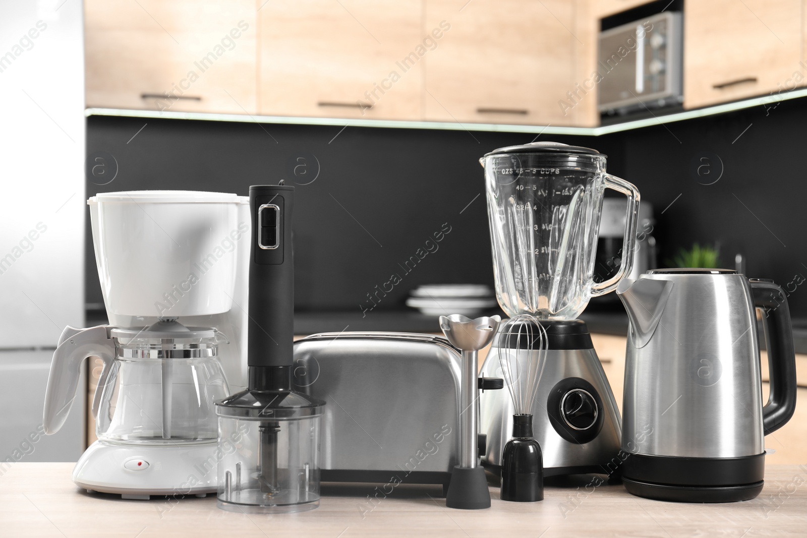 Photo of Modern domestic appliances on wooden table in kitchen
