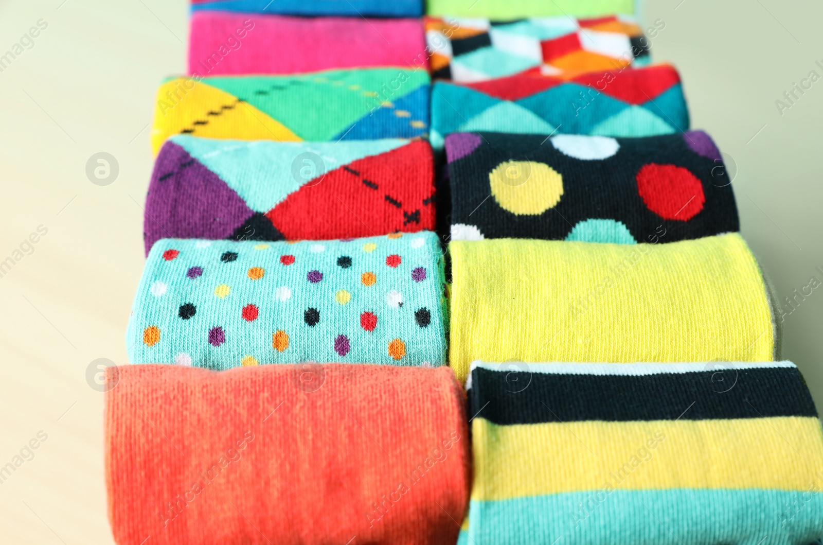 Photo of Rolled colorful socks on light background, closeup