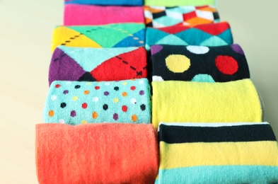 Photo of Rolled colorful socks on light background, closeup